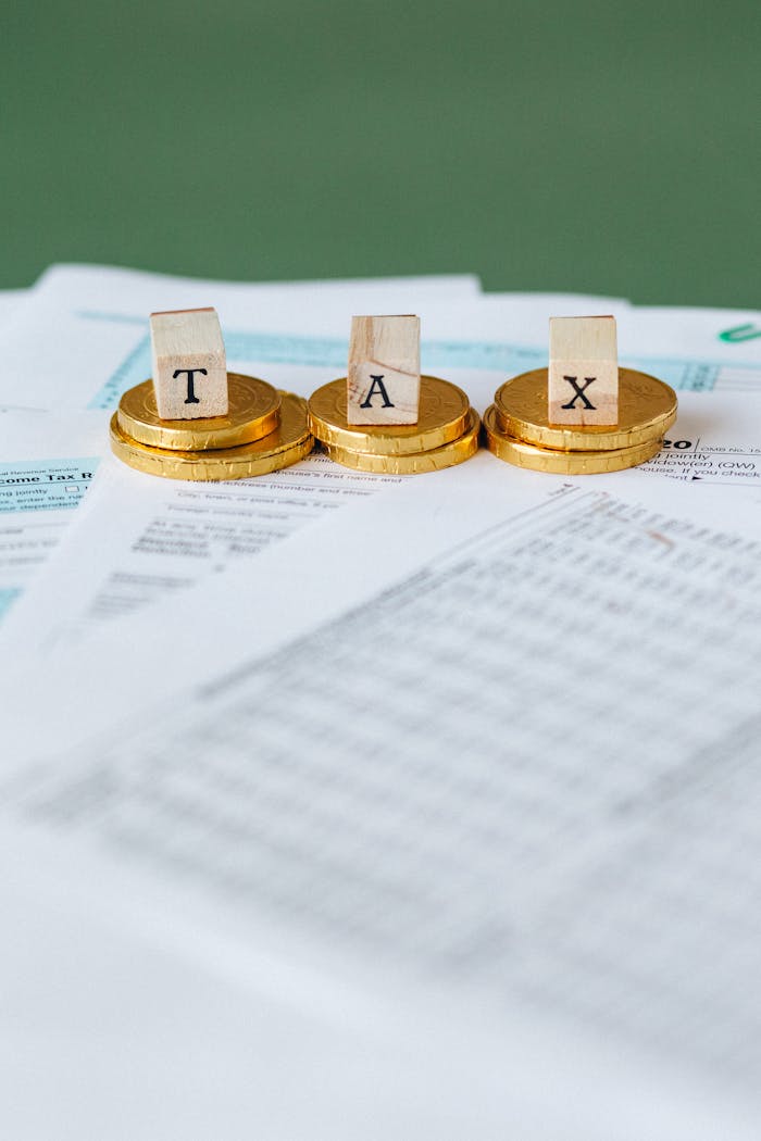 Staged image of gold coins with tax letter tiles on documents.